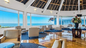 Eine geräumige Lobby mit hoher Decke, großen Fenstern und Blick auf das Meer.