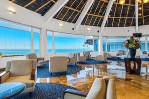 A spacious lobby with a high ceiling, large windows, and a view of the sea. - Elegant Suite With Ocean-view Pools, hot Tub, Gym, Balcony & Full Kitchen (Puerto Vallarta)