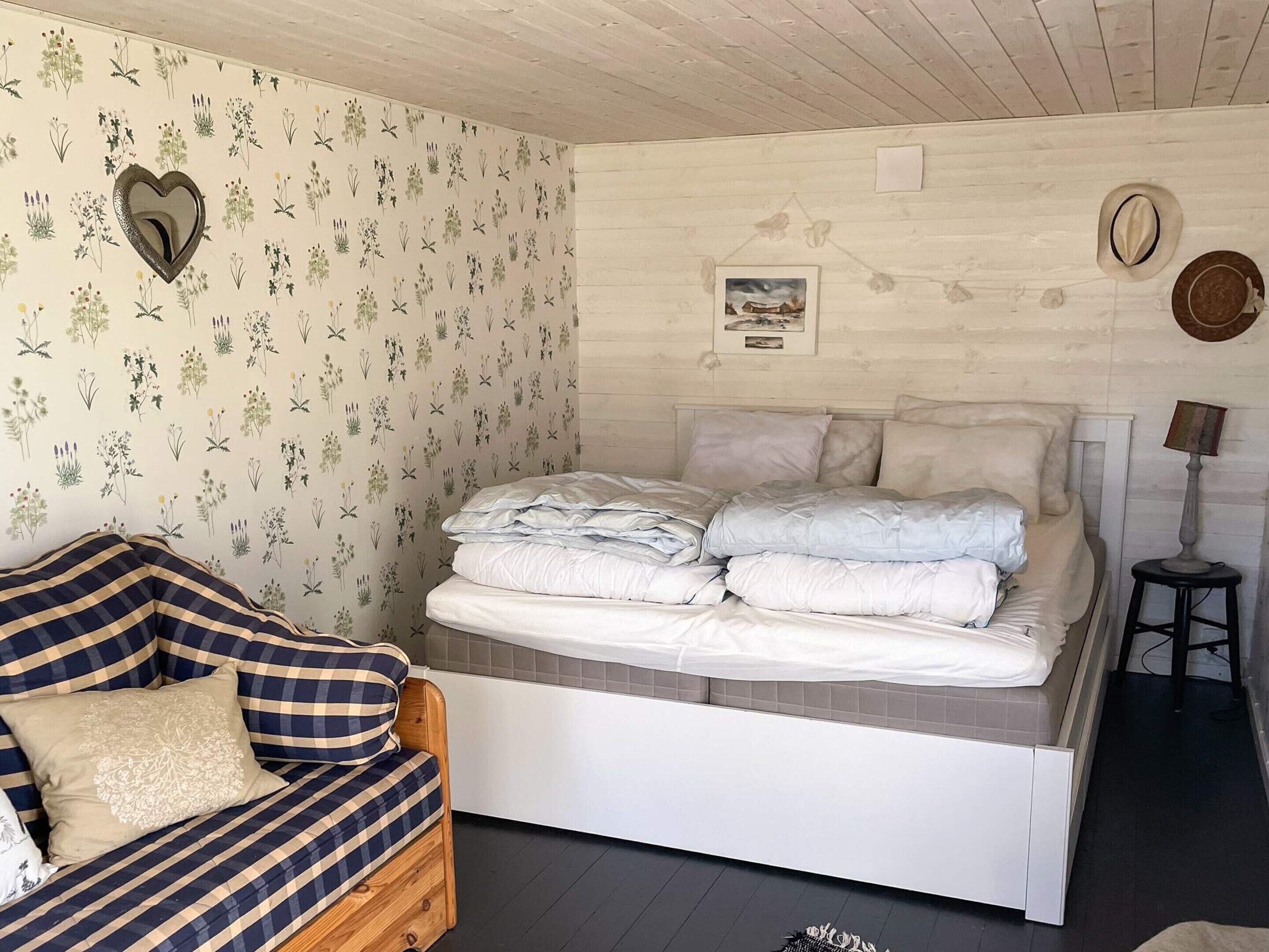 Une chambre à coucher avec un lit, un canapé, un miroir et un tableau au mur.