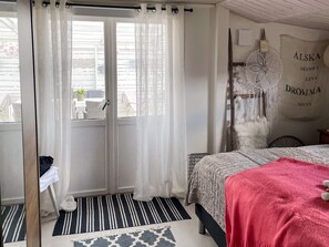 A bedroom with a bed, a window with curtains, a bedside table, and a wall with a decorative item. - 6 Person Holiday Home in Skummeslovsstrand (Skummesloevsstrand)