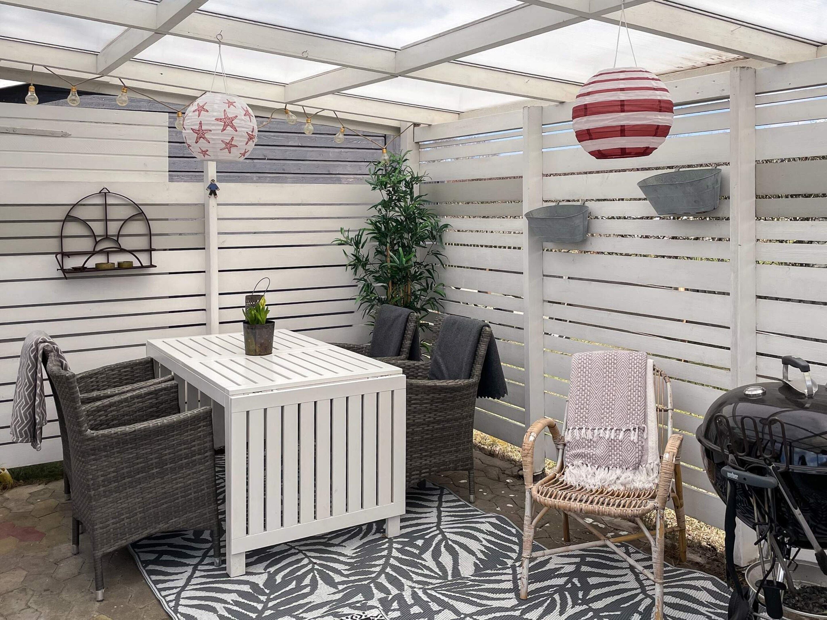 A patio with wicker furniture, a white table, and a grill.