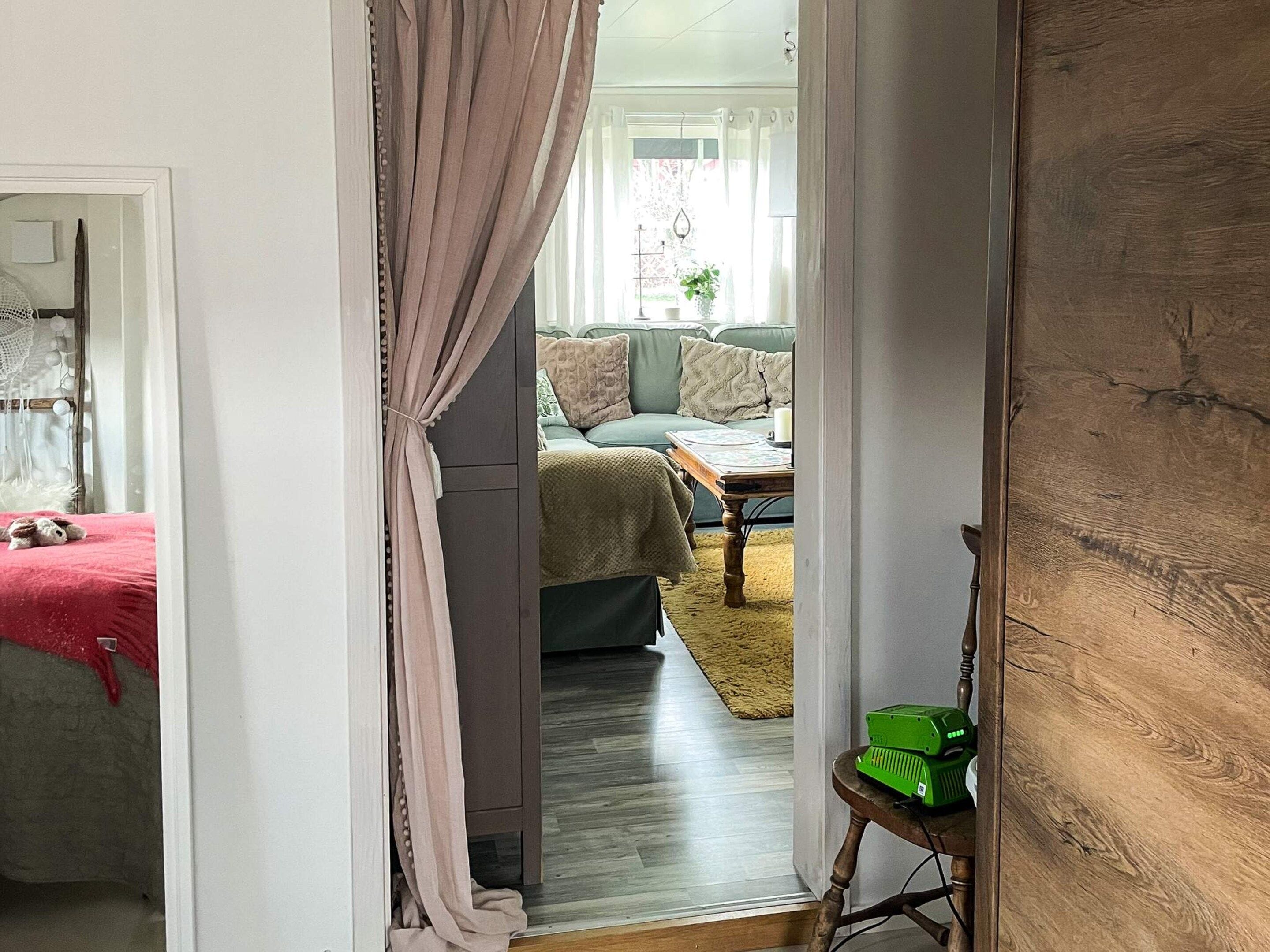 An interior view of a room with a wooden floor, a green table, and a green object on a wooden stool.