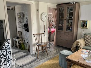 Ein Zimmer mit einem Holzbett, einem kleinen Tisch, einem Schrank mit Glastüren und einer Uhr an der Wand.