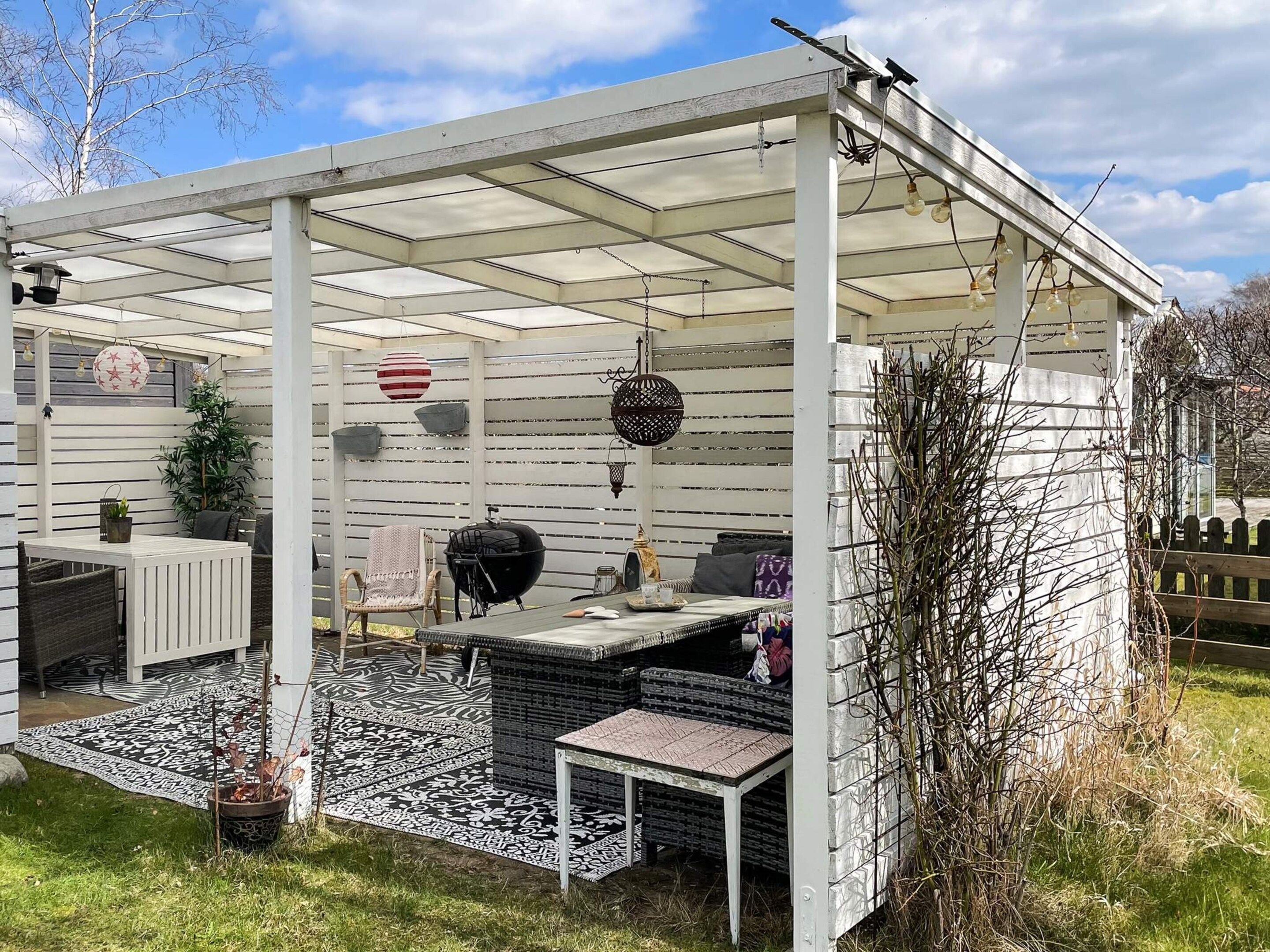 A covered outdoor patio with a grill, seating, and decorative elements.