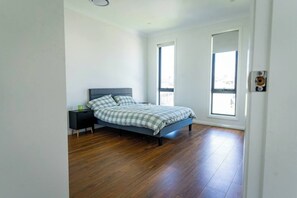 Une chambre à coucher avec un lit, une table de chevet et de grandes fenêtres.