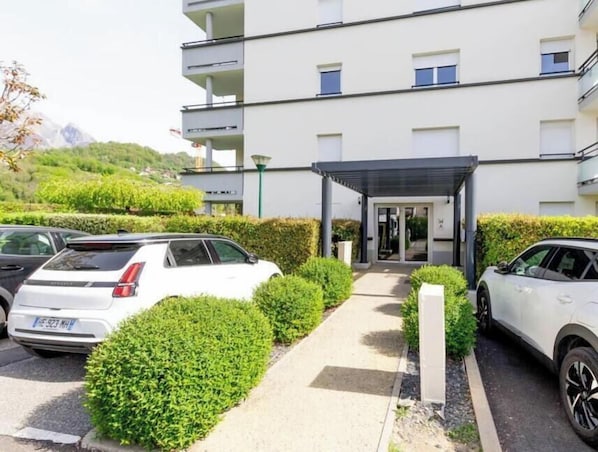 A modern building with a covered entrance, parked cars, and well-maintained greenery. - Edelweiss A2 - ALBERTVILLE (ALBERTVILLE)