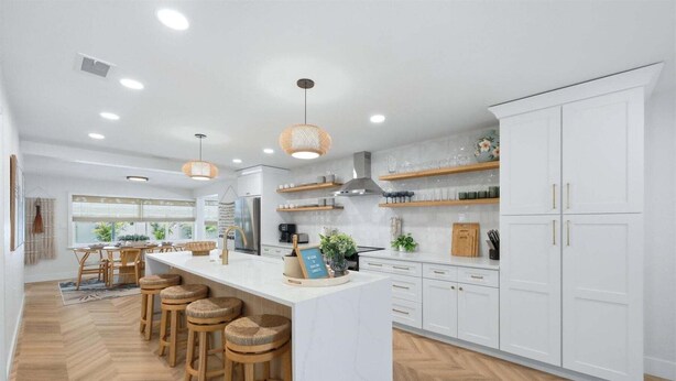 A modern kitchen with a central island, wooden stools, white cabinetry, and pendant lighting. - 🦩Chasing Sunsets at St Pete Beach🦩 (Saint Petersburg)