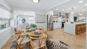A modern kitchen with a central island, white cabinetry, and a stainless steel refrigerator. - 🦩Chasing Sunsets at St Pete Beach🦩 (Saint Petersburg)