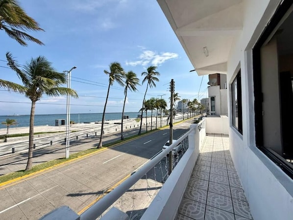 Ein Balkon mit Blick auf einen Strand, Palmen und einen klaren Himmel.