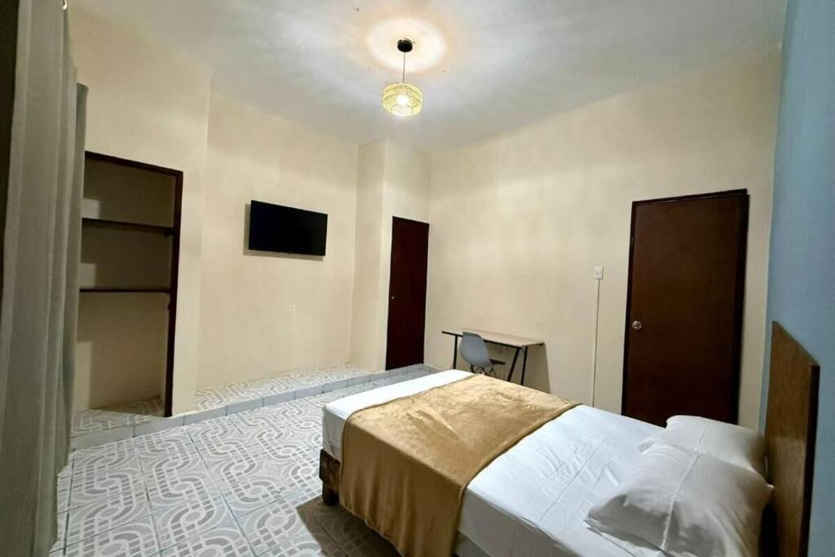 A room with a bed, a desk, a chair, a wardrobe, and a television on the wall.
