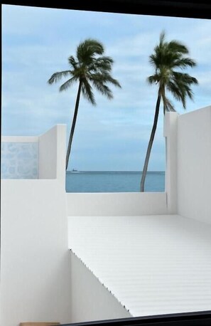 Ein Balkon mit Blick auf das Meer und zwei Palmen.