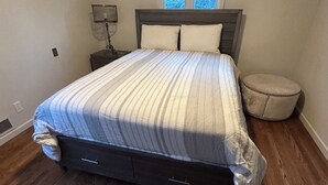 A bedroom with a bed, a nightstand, a lamp, a window, and a round ottoman. - Perfect fit for FIFA World Cup visitors! 4-bedroom house in close-by Clifton (Clifton)