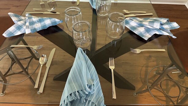 A dining table with a glass top, surrounded by metal chairs, and set with cutlery and glassware. - Perfect fit for FIFA World Cup visitors! 4-bedroom house in close-by Clifton (Clifton)