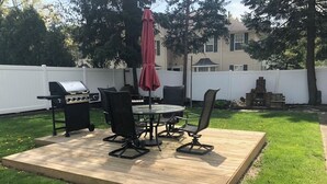 A backyard with a wooden deck, a grill, outdoor furniture, and a red umbrella. - Perfect fit for FIFA World Cup visitors! 4-bedroom house in close-by Clifton (Clifton)