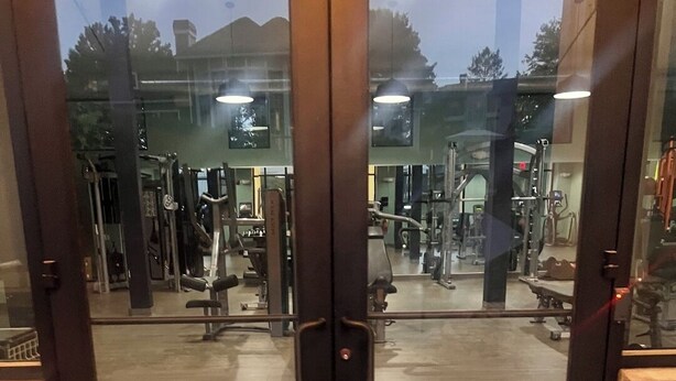 Un gimnasio con puertas espejadas y equipamiento de ejercicio.