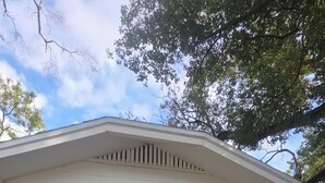 Una casa bianca con un portico, una porta nera e il numero '3411' sulla parete.