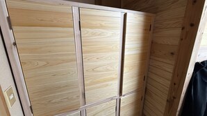 A wooden wardrobe with multiple compartments, a visible handle, and a door with a small window. - BungonoSato (Kusu)
