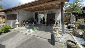 A traditional Japanese building with a tiled entrance, stone statues, and a wooden roof. - BungonoSato (Kusu)