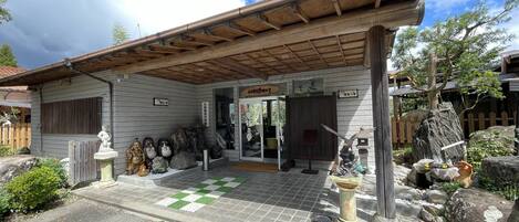 Un bâtiment traditionnel japonais, avec une entrée carrelée, des statues de pierre et un toit en bois.