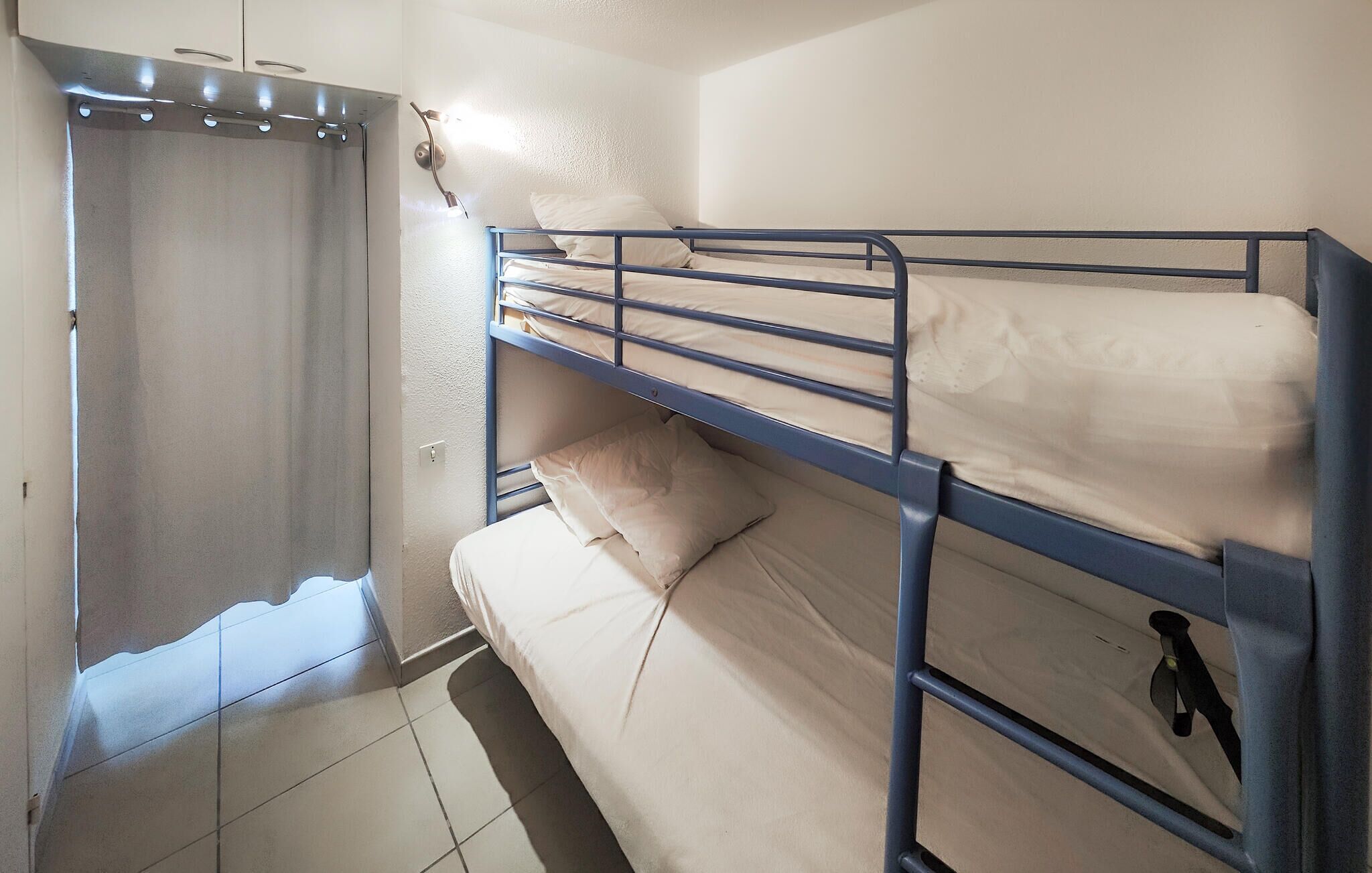 Une chambre avec un lit superposé, un rideau de douche, un porte-serviettes et un luminaire.