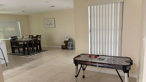 A room with a foosball table, a dining area with a table and chairs, and a window with blinds. - Beautiful 3-bedroom house with AC in adorable New Port Richey (New Port Richey)