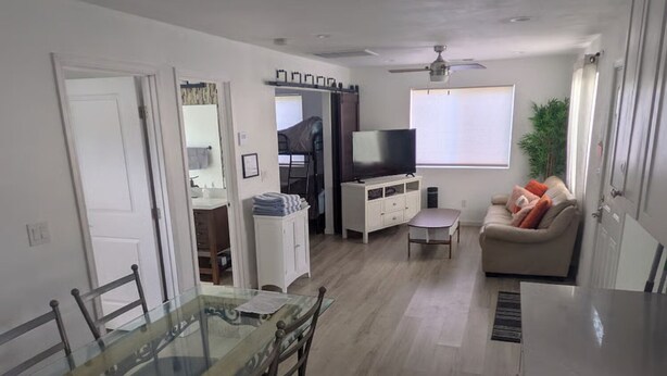 A compact living space with a dining table, chairs, a sofa, a TV, and a ceiling fan.