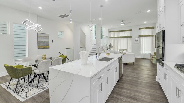 A modern kitchen with a marble island, white cabinetry, and a dining area with a glass table and chairs. - Luxe 3 BR w/ Garage + Patio, 5 min NRG & Med Ctr (Houston)