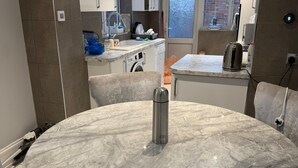 A modern kitchen with a marble dining table, built-in appliances, and a view to the outside. - Two bedroom independent house with parking & WiFi (Romford)
