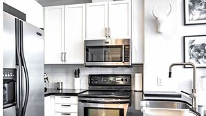 Una cucina moderna con elettrodomestici in acciaio inossidabile, mobili bianchi e forno a microonde integrato.