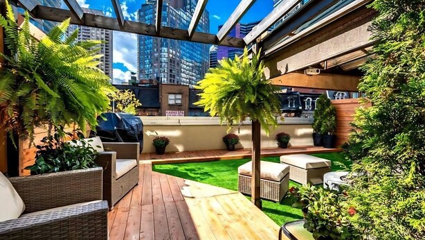 Una terrazza sul tetto con pavimento in legno, mobili da esterno e piante in vaso.