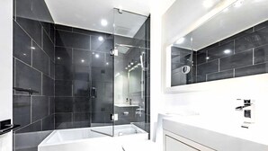 Un bagno moderno con doccia vetrata, una vasca da bagno bianca e un ampio specchio sopra il lavabo.