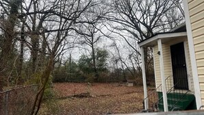 A house with a porch, a fenced yard, and leaf-covered ground. - 4BR Home Minutes from Mercedes‑Benz Stadium — FIFA 2026 Full‑Event Rental (Atlanta)