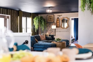 A living room with a sofa, a coffee table, a plant, and a mirror on the wall. - Luxury Hocking Hills Cabin| Views + Epic Game Room (South Bloomingville)