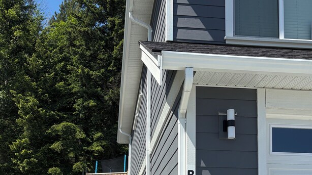 Un immeuble résidentiel doté d’un garage, d’un chemin menant au garage et d’une clôture en bois.