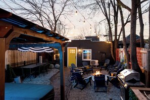 An outdoor patio with a grill, seating area, and a wooden pergola. - Lou Luxe- Speakeasy, EPIC Arcade, Hottub & FirePit (St. Louis)