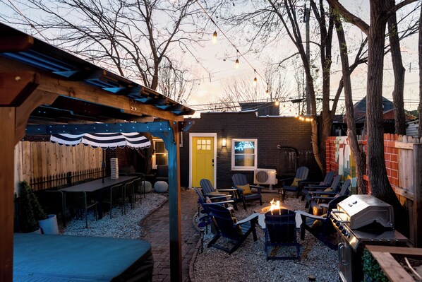 Un patio exterior con una parrilla, zona de estar y una pérgola de madera.