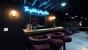 Eine Bar mit Neonreklame, Barhocker, einer Theke und einem Spiegel.