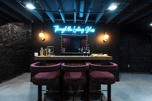 A bar area with a neon sign, bar stools, and a counter with glasses and bottles. - Lou Luxe- Speakeasy, EPIC Arcade, Hottub & FirePit (St. Louis)