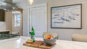 Ett kök med en bänkskiva i marmor, en flaska Pellegrino-vatten, en skål med snacks och en inramad målning av en mås på väggen.