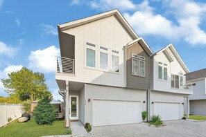 Une maison moderne à deux étages, dotée d’un garage, d’un patio couvert et d’une pelouse bien entretenue.
