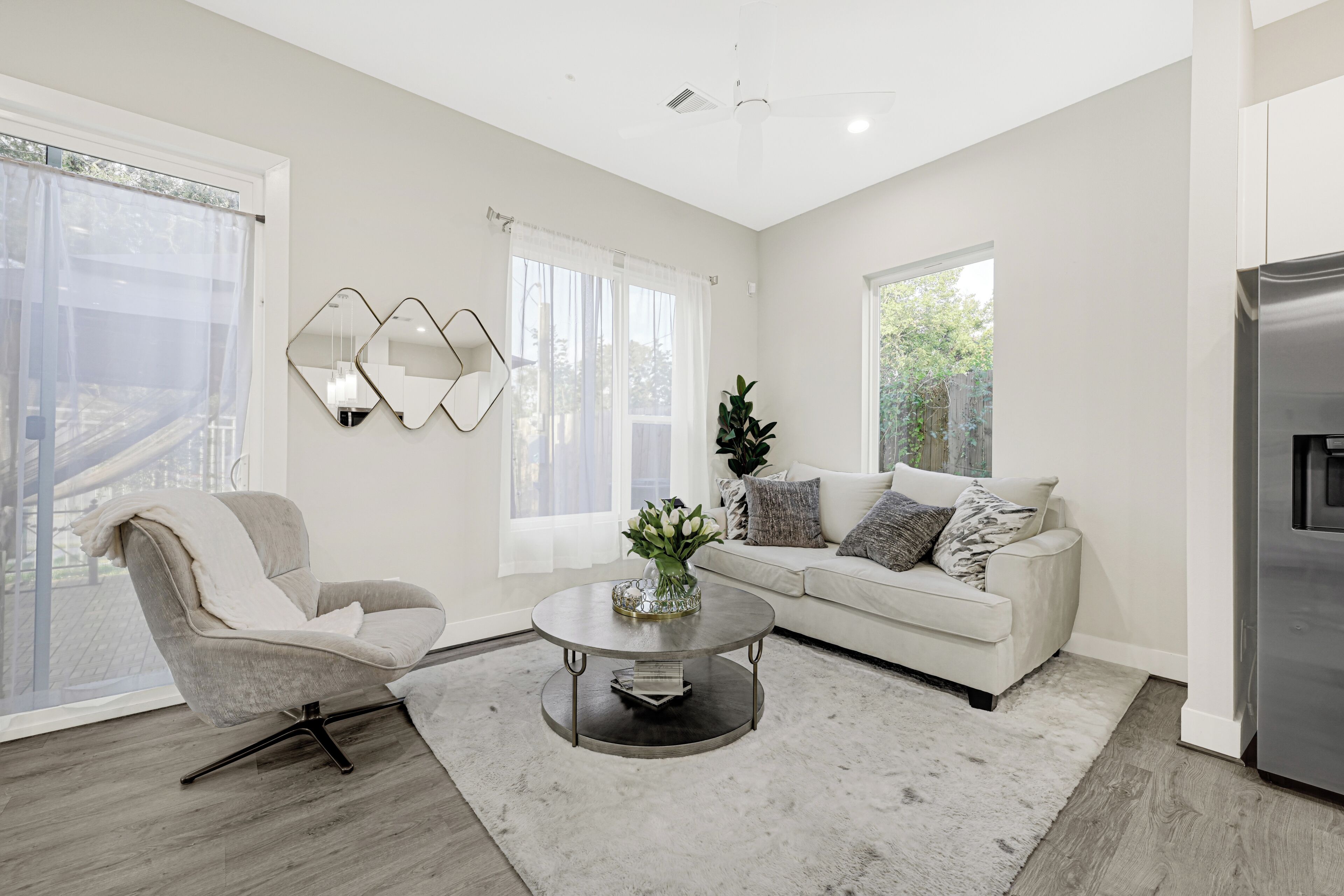 Una sala moderna con sofá, sillón, mesa de centro y ventanas amplias.