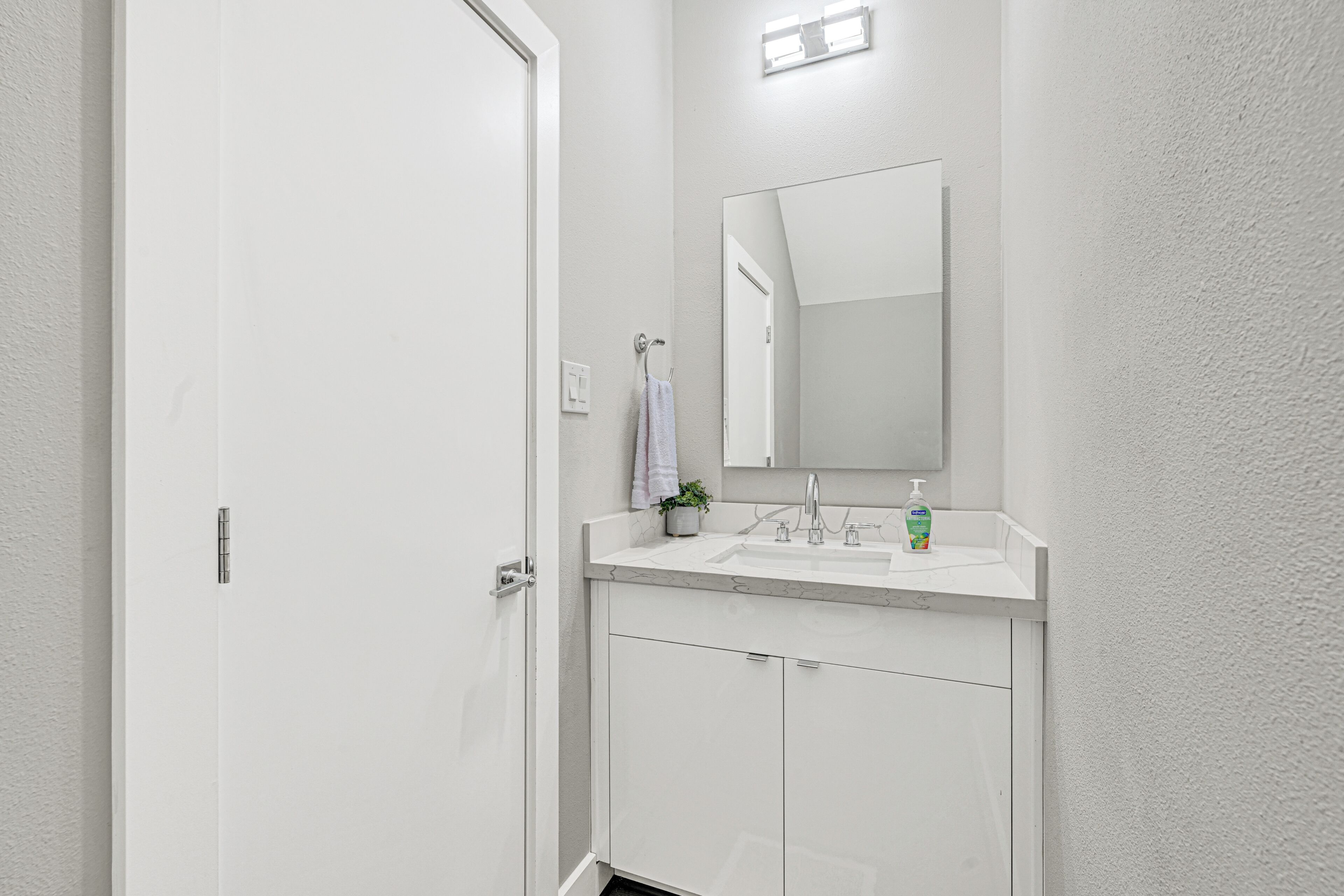 Een badkamer met een witte wastafel, spiegel en kastjes.