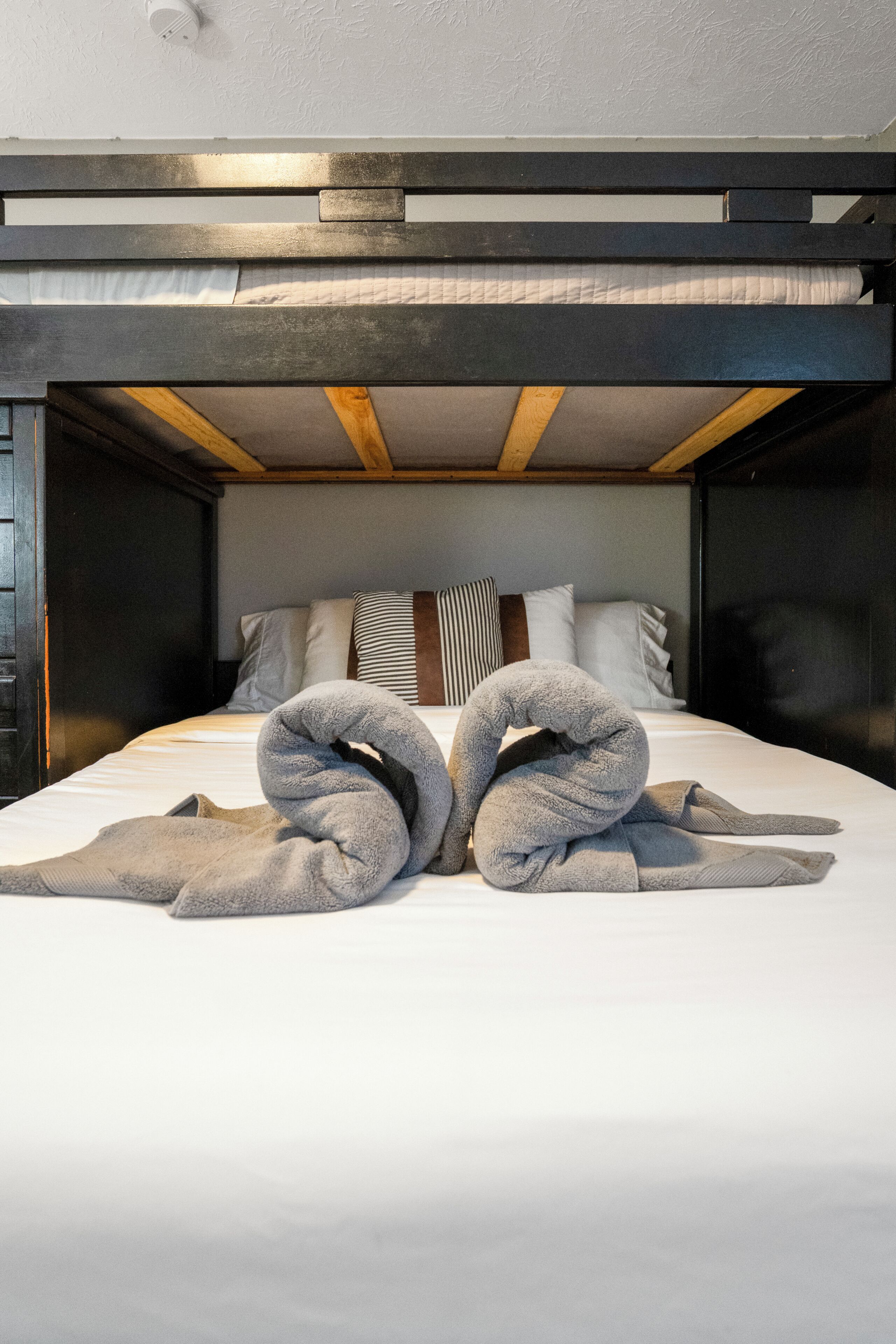 A bunk bed with a white mattress, pillows, and a towel arrangement.