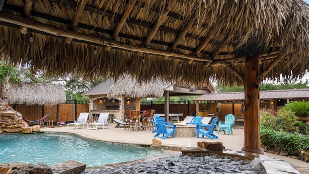 A pool area with a hot tub, lounge chairs, and a thatched roof structure. - Empress Villa Retreat (Alvin)