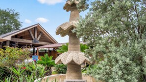 A garden with a fountain, a sign reading 'Houston,' and a building with a wooden roof. - Empress Villa Retreat (Alvin)