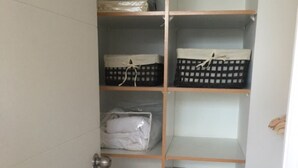 A storage closet with shelves, some containing folded items and others empty.