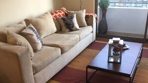A living room with a beige sofa, a coffee table, and a red rug.