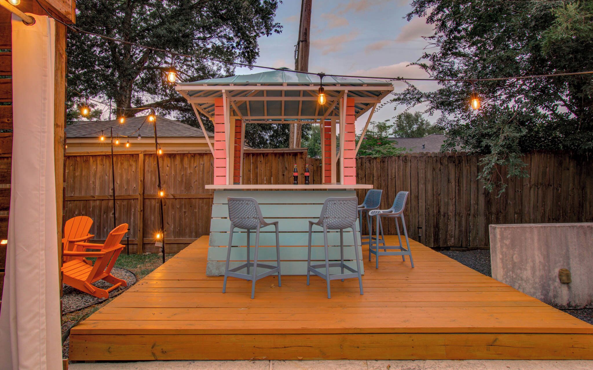 A wooden deck with a bar area, two chairs, and a table.