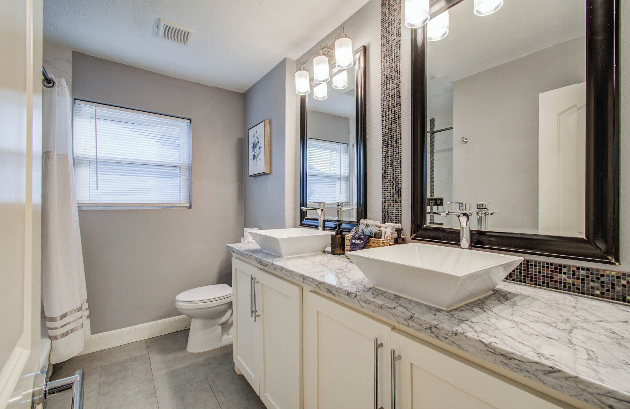 A bathroom with a white sink, a large mirror, and a toilet.