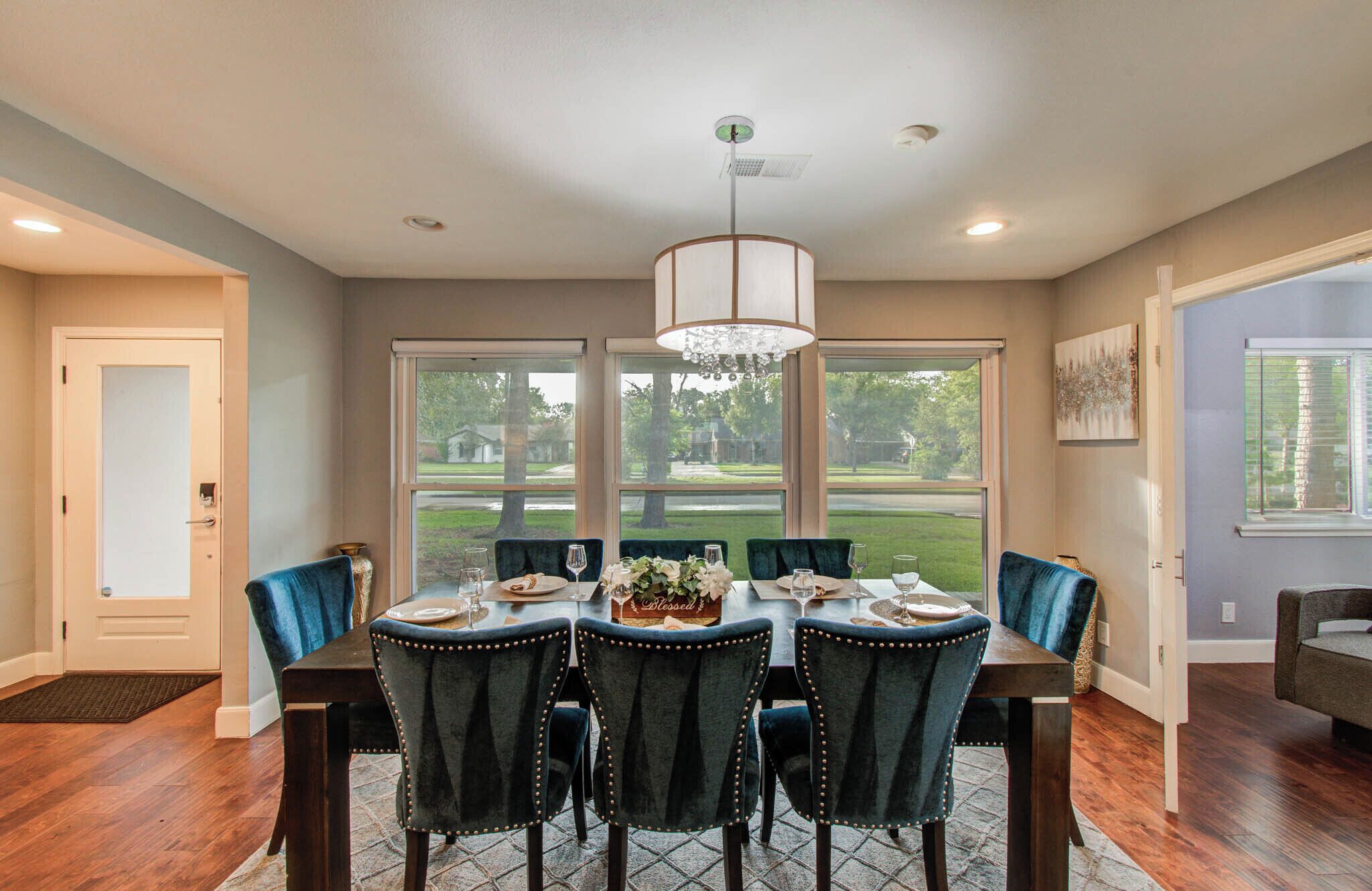 A dining room with a table set for six, large windows, and a chandelier.